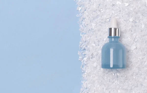 Soro ou óleo em garrafa de vidro azul com conta-gotas em backgrou nevado — Fotografia de Stock