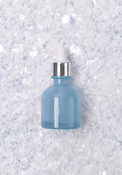 Sérum nebo olej v modré skleněné láhvi s kapátkem na zasněženém pozadí — Stock fotografie