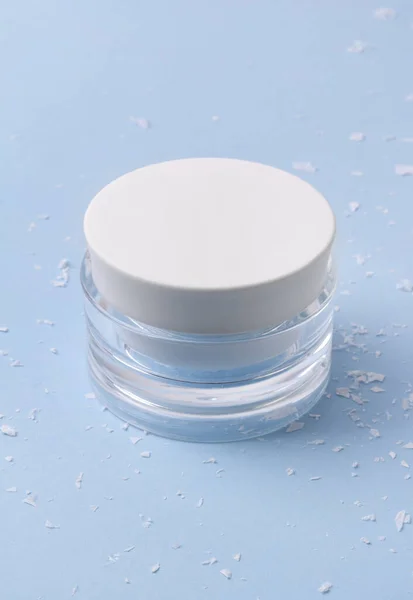 Creme cosmético em um jarro com neve artificial no fundo azul — Fotografia de Stock