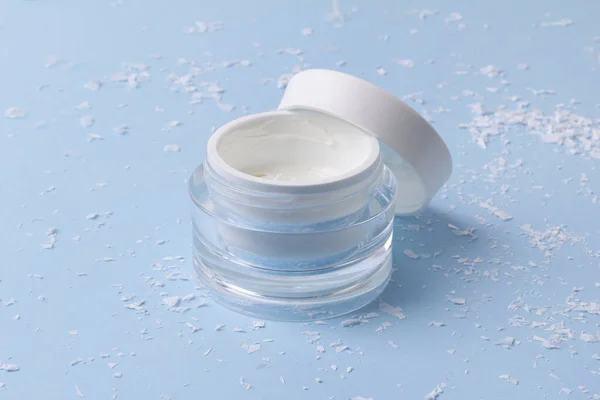 Creme cosmético em um jarro com neve artificial no fundo azul — Fotografia de Stock