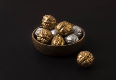 Tahta tabakta altın ve gümüş cevizler, siyah sırt.