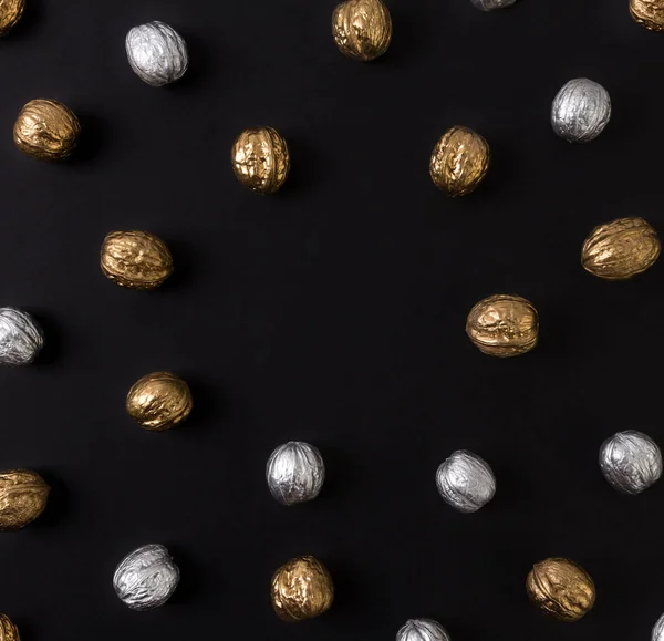 Painted golden and silver walnuts on black background