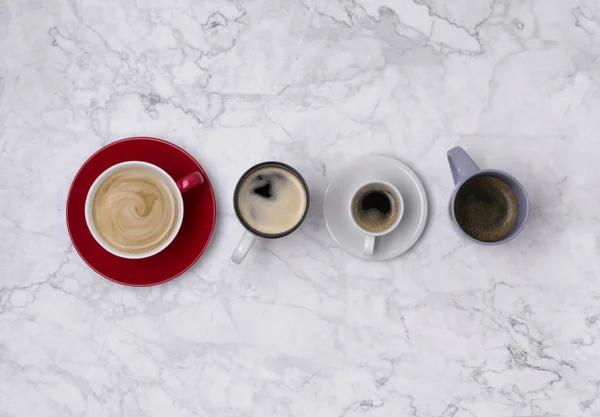 Varios café en diferentes tazas sobre fondo de mármol. Puesta plana — Foto de Stock