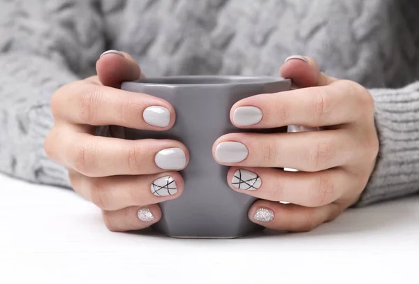 Woman's hands with geometric manicure nail design in cozy sweater