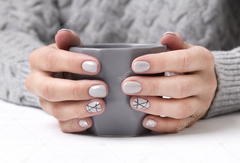 Woman's hands with geometric manicure nail design in cozy sweater