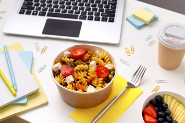 Beyaz masadaki kutuları dizüstü bilgisayarla götürmek için yiyecek. Çevrimiçi yemek servisi. Ev kavramından yeni normal çalışma.