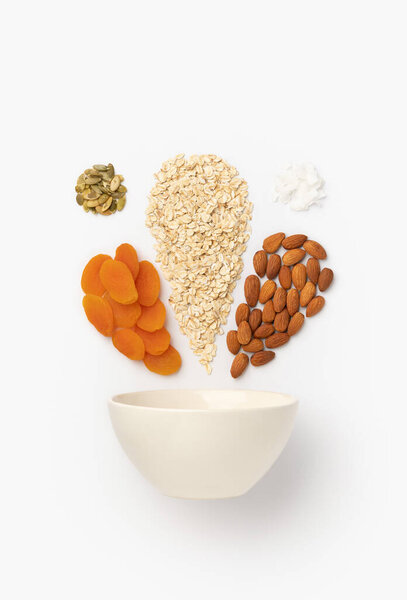 Сушеные абрикосы, миндаль, овсяные хлопья наливают в керамическую миску
