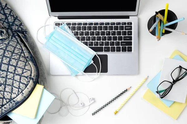 Portátil moderno con mochila y papelería en mesa blanca —  Fotos de Stock