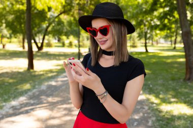 Parkta akıllı telefon kullanan güzel bir kadının portresi.