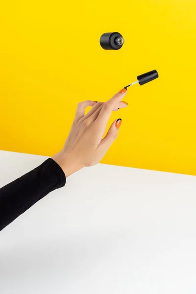 Composición creativa con manos de mujer y barniz de uñas volador — Foto de Stock