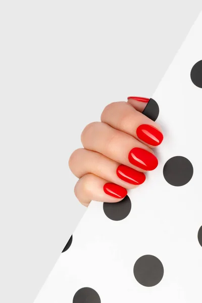 Beautiful young womans hand with red manicure on gray background — Stock Photo, Image