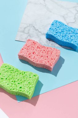 Çok renkli arka planda bulaşık yıkamak için süngerleri olan yaratıcı bir düzen. Temizlik hizmeti kavramı