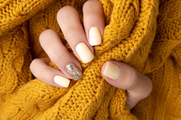 Manicured womans hands with warm wool yellow sweater