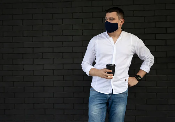 Businessman near office in protective cloth face mask. Man in casual clothes standing on the street. New social behavior new normal concept