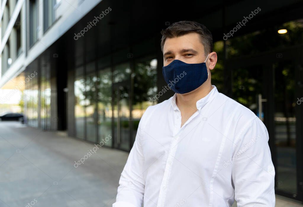Businessman near office in protective cloth face mask. Man in casual clothes standing on the street. New social behavior new normal concept