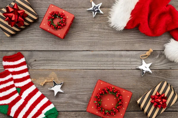 Red Santa hat, gift boxes and socks on old wooden background