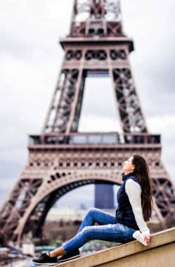 Bir kahve bir paket servisi olan restoran Eyfel Kulesi arka plan üzerinde tutan güzel genç kız kot ve beyaz bir kazak. Paris'te bir turist kavramı