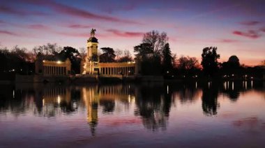 Madrid 'deki El Retiro Parkı' ndaki sakin Büyük Gölet çarpıcı bir gündoğumu parıltısını yakalıyor. Görkemli Alfonso XII anıtını yansıtması, tarihin ve huzurlu doğanın bir karışımını sembolize eder.