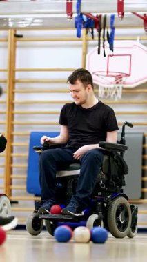 A wheelchair boccia player in intense concentration as they prepare to make a strategic move during a competitive game. Boccia is an adaptive sport for individuals with cerebral palsy.