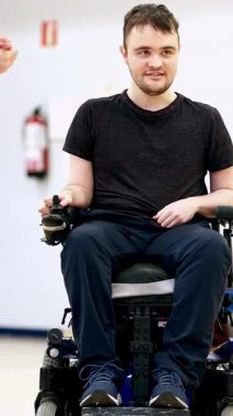A man in a wheelchair actively participating in boccia classes, showcasing determination and inclusion in adaptive sports for individuals with disabilities in a supportive environment.