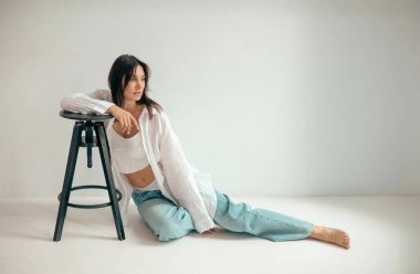 Genç bayan stüdyoda düşünceli bir şekilde oturuyor. Kadın karakteri.