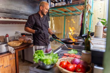 Şef açık ateşte sulu bir burger pişiriyor.