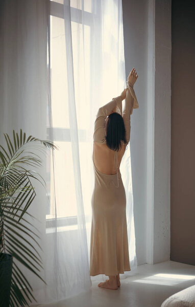 Young thoughtful woman in a long dress in the studio. Light thoughtfulness and dreaminess