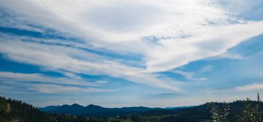 Mavi gökyüzü ve beyaz bulutlu güzel bir dağ manzarası.
