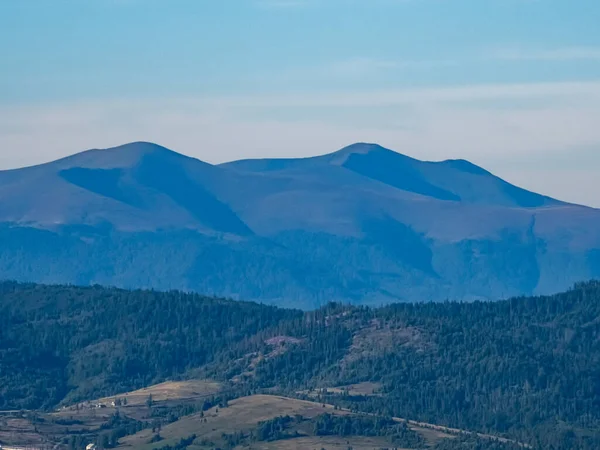 Güneşli bir günde mavi gökyüzü ve bulutlarla güzel bir dağ manzarası.