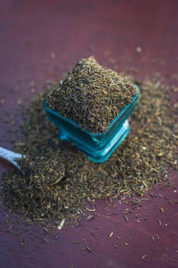 Ham şah zeera veya şah jeera, Carum carvi, kimyon tohumu kahverengi ahşap yüzey üzerinde mavi bir kasede yakın çekim.