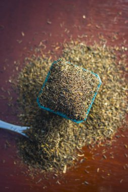 Ham şah zeera veya şah jeera, Carum carvi, kimyon tohumu kahverengi ahşap yüzey üzerinde mavi bir kasede yakın çekim.