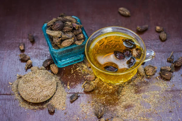 Close up of tea of Black cardamom with its powder and raw whole black cardamom.