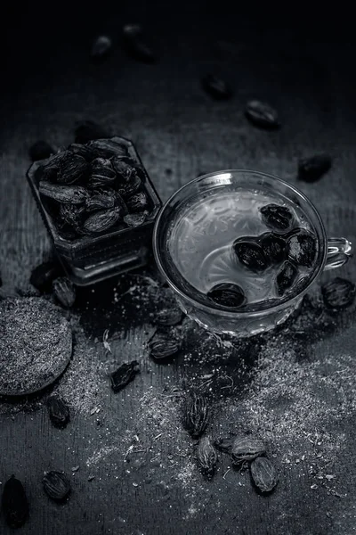 Close up of tea of Black cardamom with its powder and raw whole black cardamom.