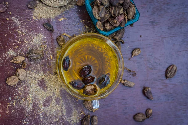 Close up of tea of Black cardamom with its powder and raw whole black cardamom.