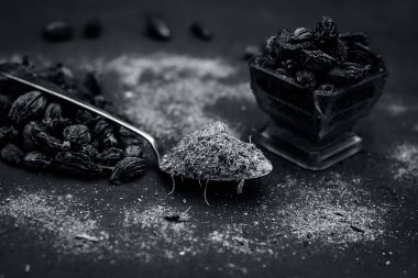 Onun tozu ile mavimsi bir yüzey üzerinde ham siyah kakule.;