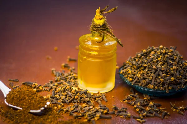 Close up of clove with its oil and powder in a white fork.