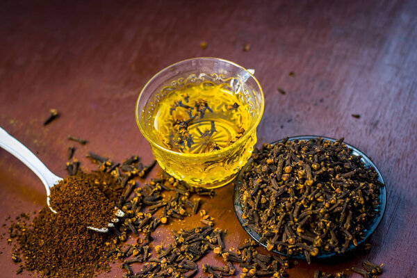 Close up view of cloves with its tea in a transparent cup.