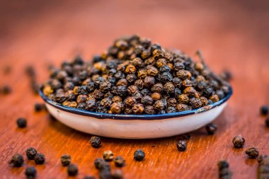 Ahşap yüzey üzerinde ham siyah biber tabak içinde görünümü kadar kapatın.