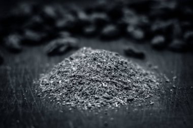 Onun toz bir ahşap yüzey üzerinde ham siyah kakule