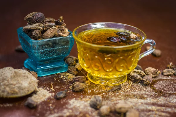 Close up view of Black cardamom tea with its powder and raw whole black cardamom