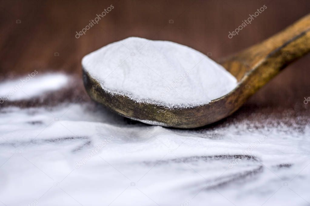 Baking soda  in a wooden scoop on wooden surface
