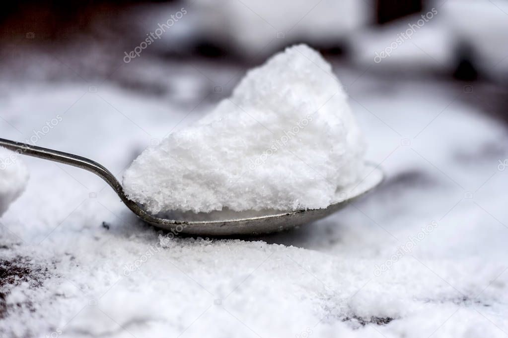 Common salt  in a wooden scoop on wooden floor