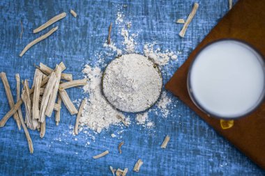 Ayurveda ot satavari tozu ve süt cam görünümünü kapat.