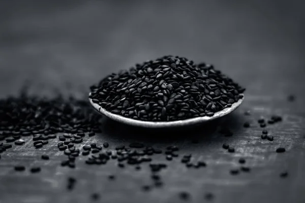 Close up view of black sesame seeds in a small plate on a wooden surface