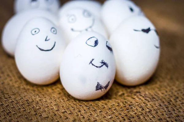 Close up view of eggs with funny faces drawn on them.