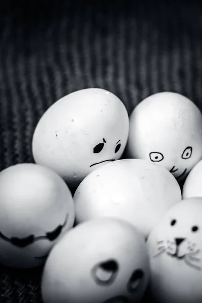 Close up view of eggs with funny faces drawn on them.