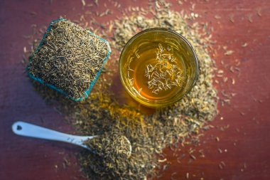 Siyah kimyon tohumu ve saydam bir cam ahşap yüzeyde ayıklanan su