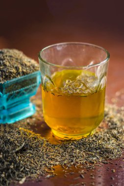 Siyah kimyon tohumu ve saydam bir cam ahşap yüzeyde ayıklanan su