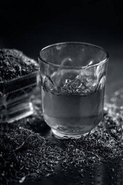 Siyah kimyon tohumu ve saydam bir cam ahşap yüzeyde ayıklanan su