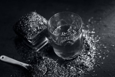 Siyah kimyon tohumu ve saydam bir cam ahşap yüzeyde ayıklanan su